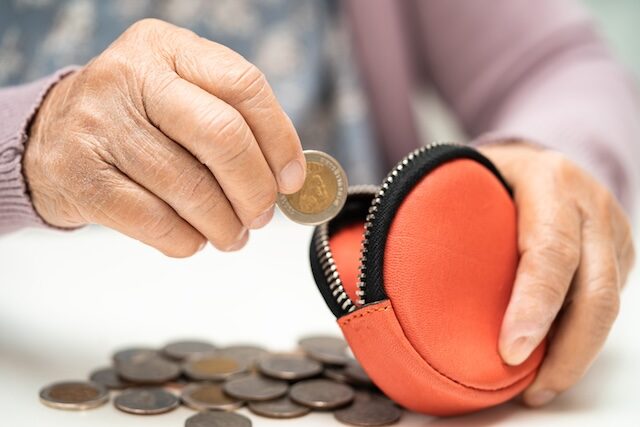 Asian senior woman holding counting coin money in purse. Poverty, saving problem in retirement.