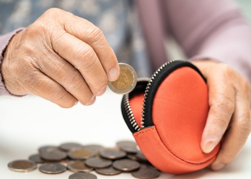 Asian senior woman holding counting coin money in purse. Poverty, saving problem in retirement.