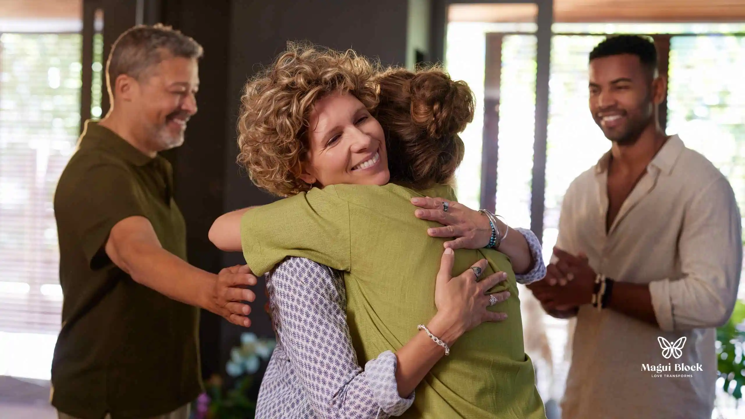 dos hombres y dos mujeres con expresiones alegres y tranquilizadoras, las mujeres se abrazan Cómo la sanación sistémica impacta la vida diaria metodo magui block