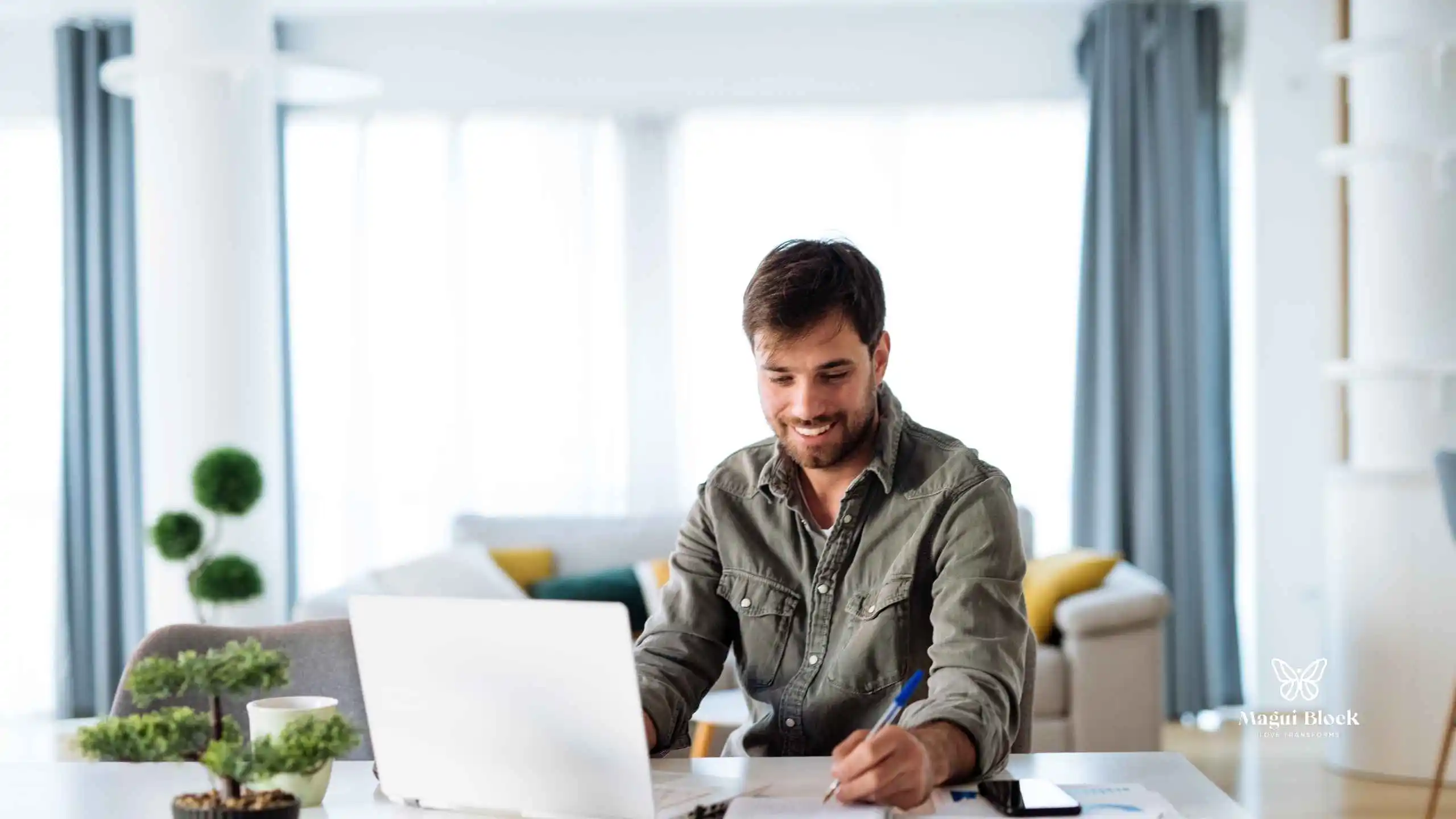 hombre en frente de su computador escribe en un cuaderno espacio iluminado formación terapeuta magui block